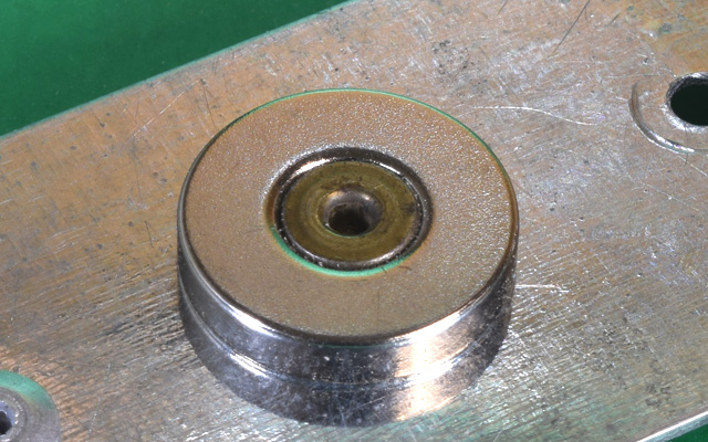 Magnet held by steel rivet