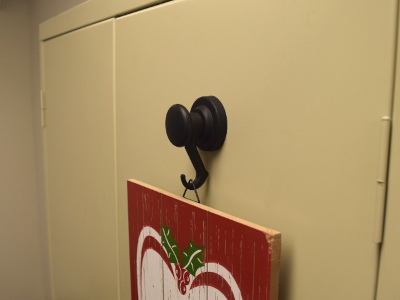 Rubber hook magnet holding christmas sign on a metal filing cabinet