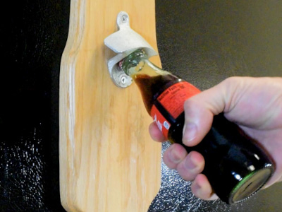 Magnetic bottle opener on fridge opening a coke bottle