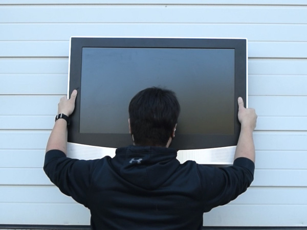 Person mounting tv on the side of a house with magnets