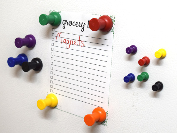 Multi colored pushpin thumbtack magnets holding picture on fridge