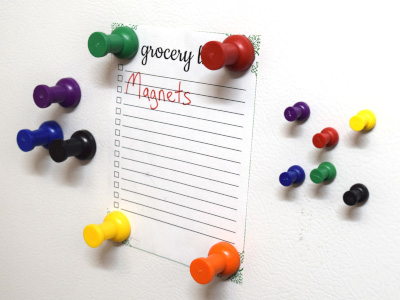 Pushpin magnets holding a shopping list on fridge