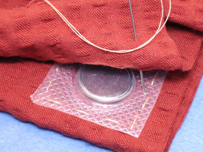 Magnet being sewn into fabric as a fastener